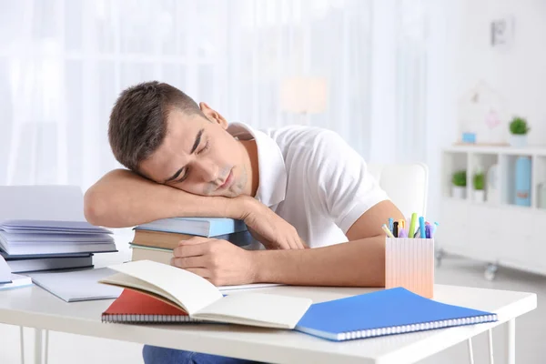 Vermoeide student slapen op stapel boeken achter zijn bureau. Voorbereiding voor examen — Stockfoto