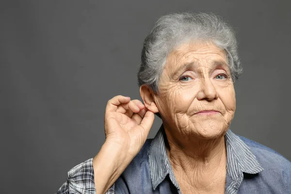 Mujer mayor con problemas de audición sobre fondo gris — Foto de Stock