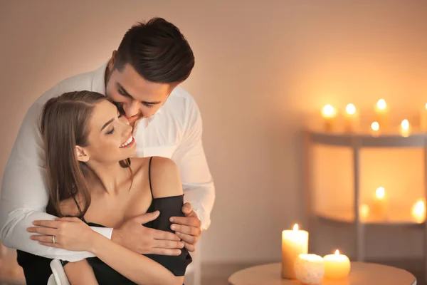 Happy young couple in room with burning candles — Stock Photo, Image