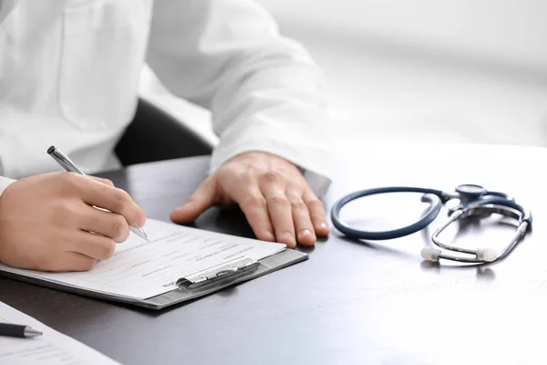 Läkare fylla i blanketten för sjukförsäkring vid bord — Stockfoto