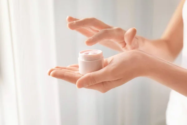 Jeune femme tenant pot de crème pour les mains, gros plan — Photo