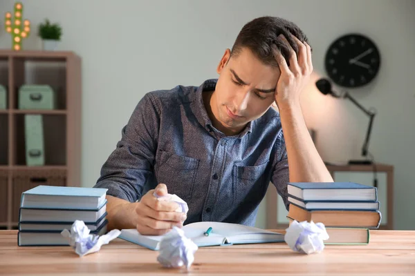 Mannelijke student voorbereiding voor examen aan tafel binnenshuis — Stockfoto