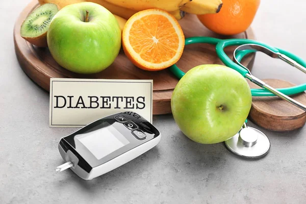 デジタル Glucometer と灰色の背景に果物 糖尿病の食事療法 — ストック写真
