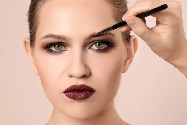 Professionell visage konstnären tillämpa makeup på kvinnans ansikte på ljus bakgrund — Stockfoto