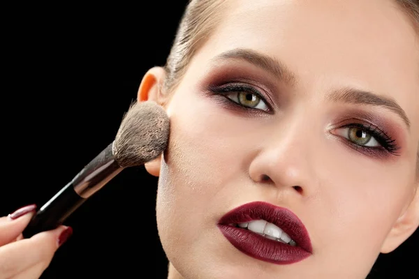 Professionele visage kunstenaar toepassing van make-up op vrouw gezicht op zwarte achtergrond — Stockfoto