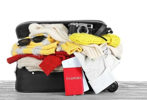 Mala aberta com roupas quentes, documentos e câmera fotográfica em mesa de madeira contra fundo branco. Conceito férias de inverno — Fotografia de Stock