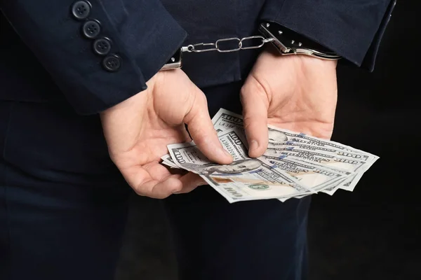 Businessman in handcuffs holding bribe on black background, closeup — Stock Photo, Image