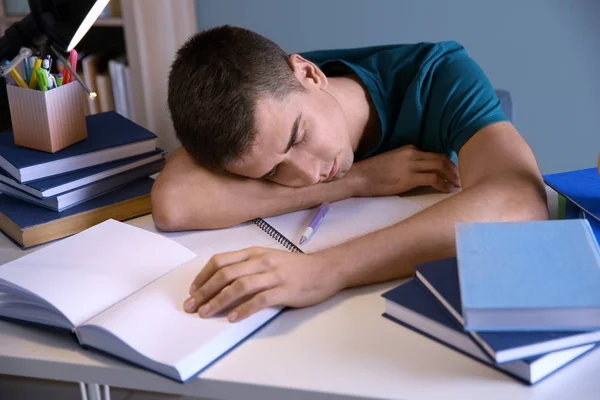 Vermoeide student slapen achter zijn Bureau binnenshuis. Voorbereiding voor examen — Stockfoto