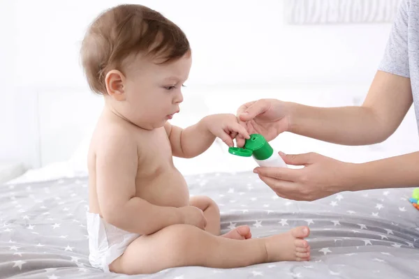 妇女在她的婴孩应用身体奶油在她的室内 — 图库照片