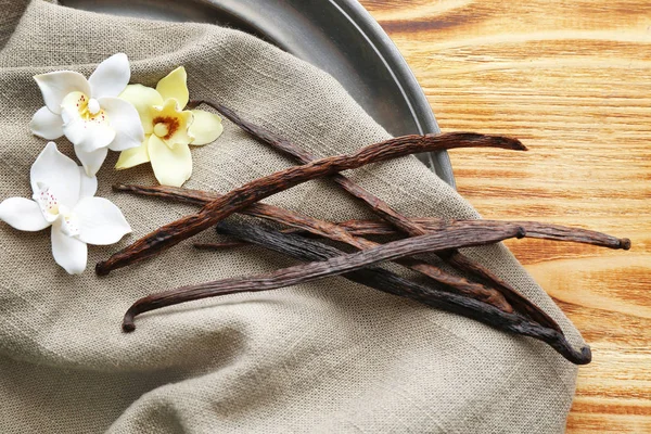 Vanilla sticks and flowers on grey fabric — Stock Photo, Image