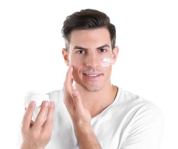 Hombre guapo aplicando crema facial sobre fondo blanco —  Fotos de Stock