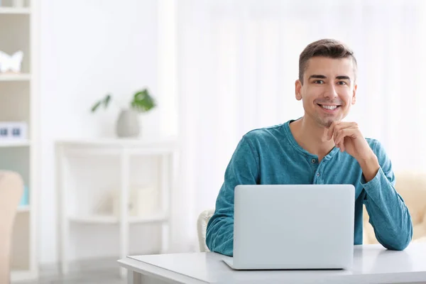 Junger Mann mit modernem Laptop am Tisch — Stockfoto