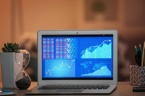 Laptop with stock data on table indoors