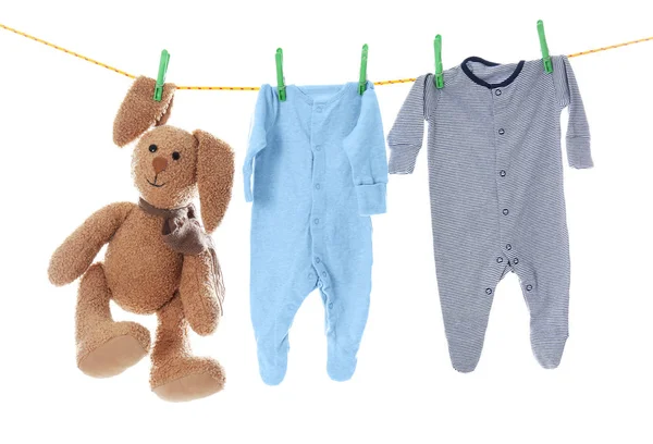 Kinderkleidung und Spielzeug auf Wäscheleine vor weißem Hintergrund — Stockfoto