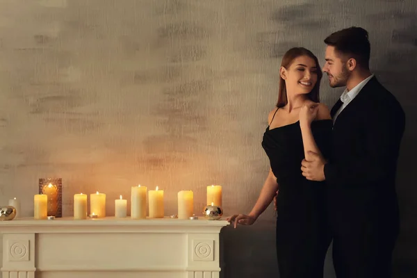 Felice giovane coppia in piedi vicino caminetto con candele accese — Foto Stock
