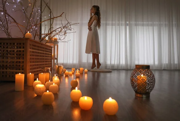 Mladá žena stojí v místnosti s hořící svíčky na podlaze — Stock fotografie