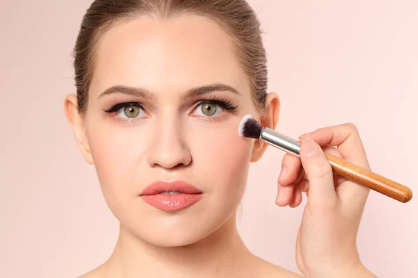 Professionell visage konstnären tillämpa makeup på kvinnans ansikte på ljus bakgrund — Stockfoto