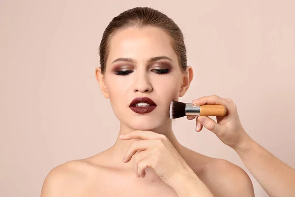 Professional visage artist applying makeup on woman's face on light background — Stock Photo, Image