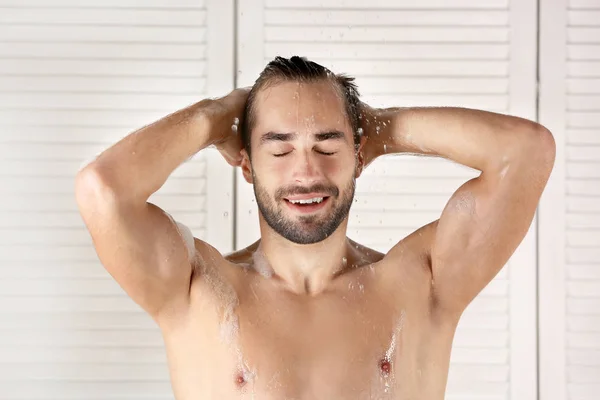 Junger schöner Mann unter der Dusche im Badezimmer — Stockfoto