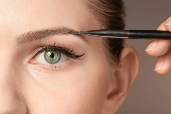 Artista profesional de visage aplicando maquillaje en la cara de la mujer sobre el fondo de color — Foto de Stock