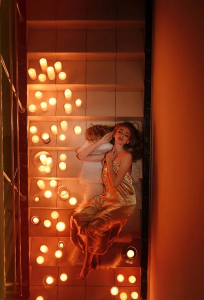 Gyönyörű fiatal nő feküdt lépcsőn égő gyertyák — Stock Fotó