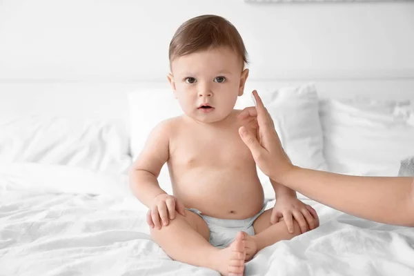 Mulher aplicando creme corporal em seu bebê dentro de casa — Fotografia de Stock