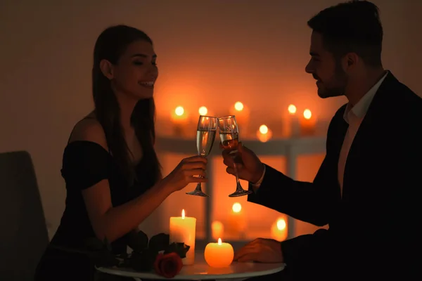 Молодая пара пьет вино, сидя за столом с горящими свечами — стоковое фото
