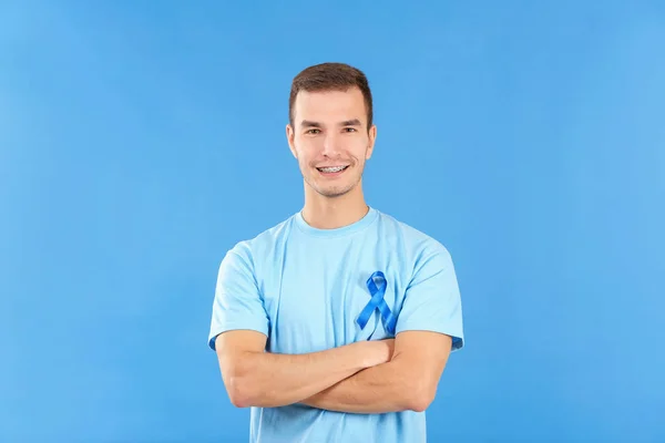 Junger Mann trägt T-Shirt mit blauer Schleife auf farbigem Hintergrund. Prostatakrebs-Aufklärungskonzept — Stockfoto