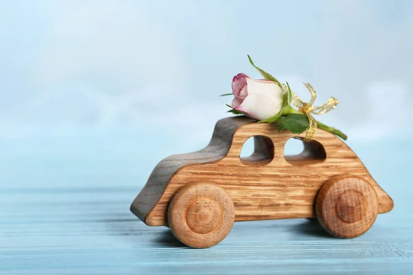 Διακοσμητικά ξύλινα αυτοκίνητο με όμορφο τριαντάφυλλο στο τραπέζι — Φωτογραφία Αρχείου