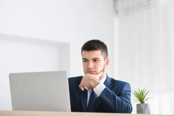 Νεαρός άνδρας στο κοστούμι που χρησιμοποιούν φορητό υπολογιστή στο χώρο εργασίας — Φωτογραφία Αρχείου