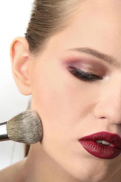 Kvinna tillämpa makeup på vit bakgrund. Professionell visage konstnär arbete — Stockfoto