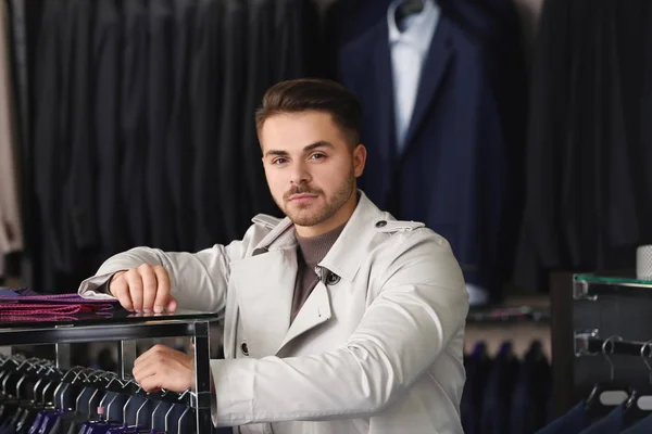 Mladý muž ve stylovém kabátě v obchodě s pánskou — Stock fotografie