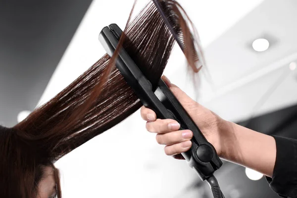 Professionele stylist straighten van haar van de vrouw in de salon, close-up — Stockfoto