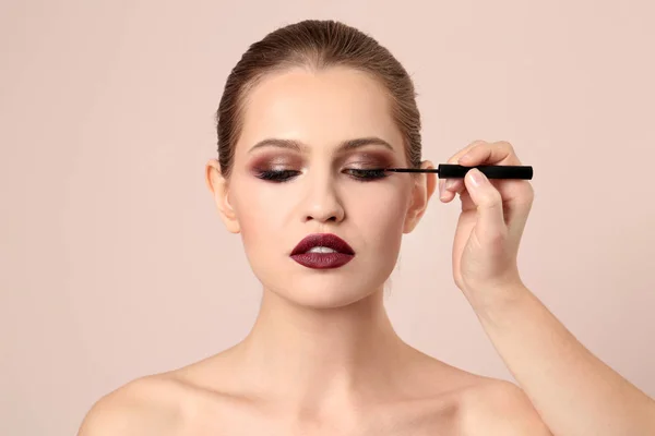 Artista de visagem profissional aplicando maquiagem no rosto da mulher no fundo claro — Fotografia de Stock