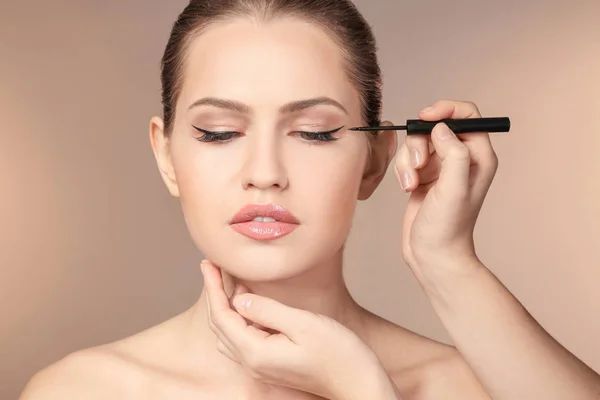 Artista profesional de visage aplicando maquillaje en la cara de la mujer sobre el fondo de color — Foto de Stock