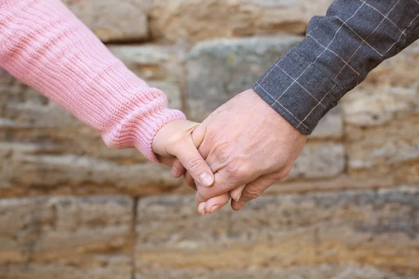 Happy mature couple holding hands outdoors near brick wall, closeup — Stock Photo, Image