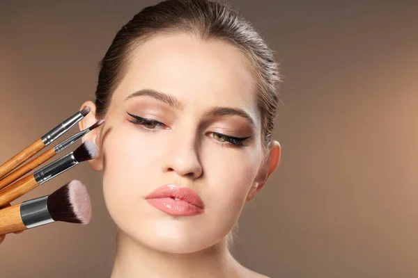 Vacker kvinna och makeup borstar på färgbakgrund. Professionell visage konstnär arbete — Stockfoto