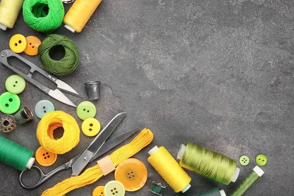 Разноцветные нити и аксессуары для шитья на сером фоне — стоковое фото