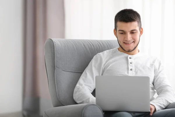 Hombre joven usando el ordenador portátil moderno en casa — Foto de Stock