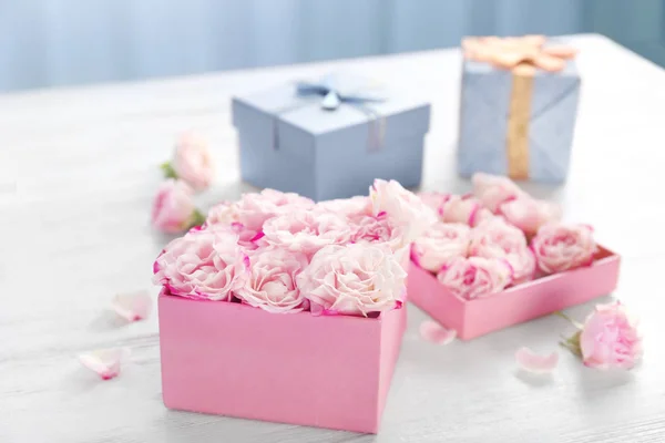 Confezione regalo con fiori su tavolo in legno — Foto Stock