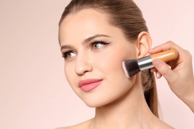 Açık renkli kadının yüzünde makyaj uygulayarak profesyonel visage sanatçı