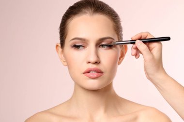 Açık renkli kadının yüzünde makyaj uygulayarak profesyonel visage sanatçı