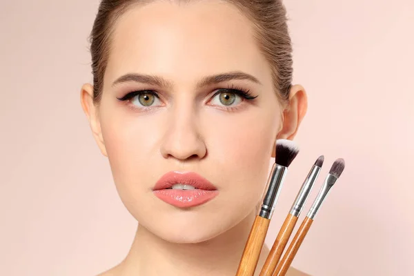 Mooie vrouw en make-up borstels op lichte achtergrond. Werk van de kunstenaar professionele visage — Stockfoto