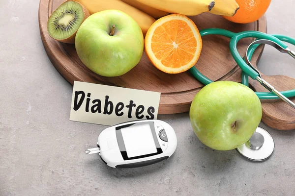 Glicosímetro digital e frutas em fundo cinza. Dieta diabética — Fotografia de Stock