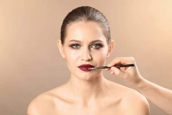 Artista de visagem profissional aplicando maquiagem no rosto da mulher no fundo de cor — Fotografia de Stock
