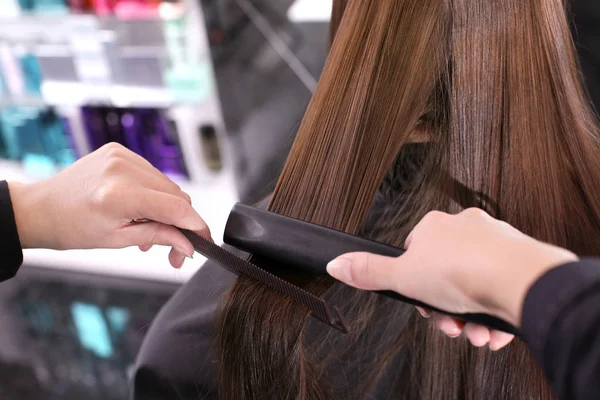 Professionele stylist straighten van haar van de vrouw in de salon, close-up — Stockfoto