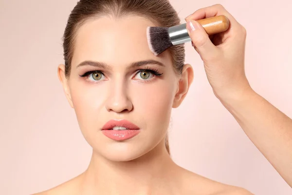 Artista de visage profesional aplicando maquillaje en la cara de la mujer sobre fondo claro — Foto de Stock