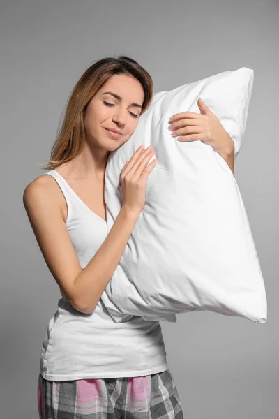 Молодая женщина с мягкой подушкой на сером фоне — стоковое фото