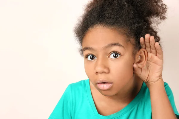 Маленькая афроамериканская девочка с проблемами со слухом на светлом фоне — стоковое фото