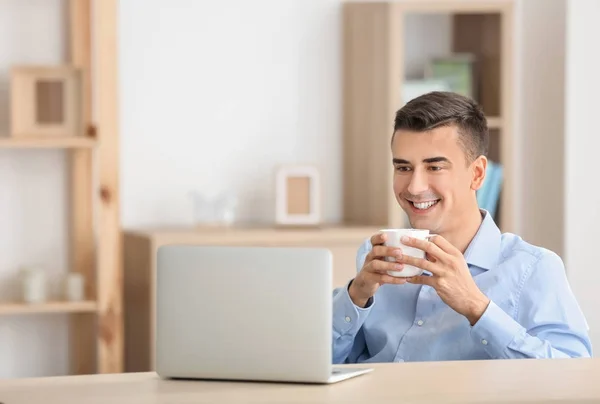 Hombre joven usando el ordenador portátil moderno en la mesa — Foto de Stock